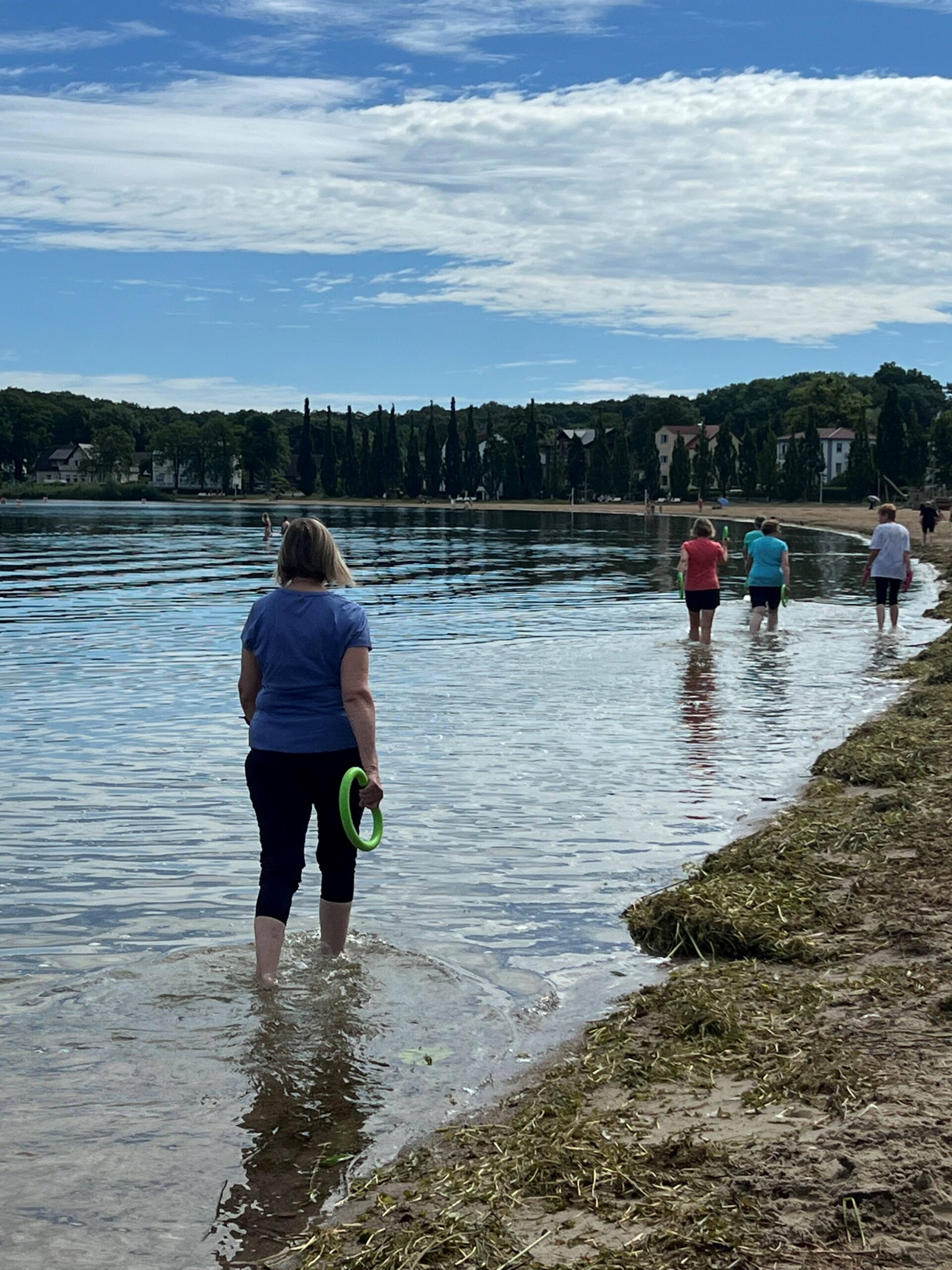 Teilnehmer laufen am Zippendorfer Strand im Wasser und schwingen mit Schwing-Ringen um sich
